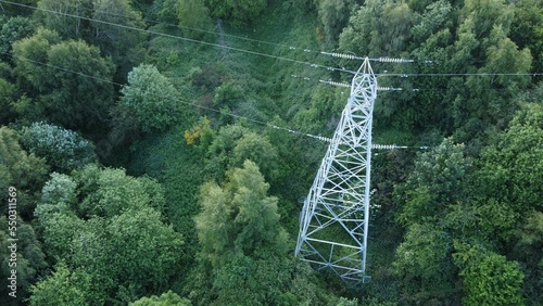 High-angle shot of a transmission tower surrounded by lush green vegetation.