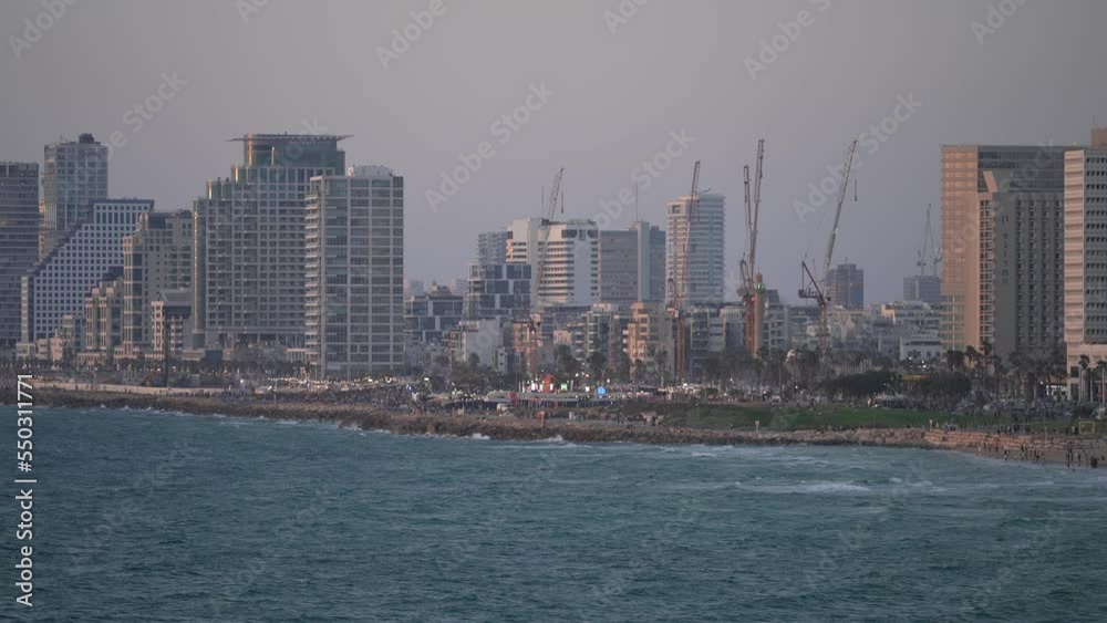 A telephoto view of a city beachfront at dusk. hotels, swim beaches, and the beautiful small wave movement in the wind. Tel Aviv, Israel. A telephoto view of a city beachfront at dusk. hotels, swim beaches, and the beautiful small wave movement in the wind. Tel Aviv, Israel.