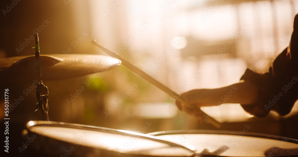 Close Up Cinematic Portrait of a Young Female Playing Drums, Using Cymbals in a Loft Music Rehearsal Studio Filled with Warm Sunset Light. Rock Band Music Artist Learning a New Drum Solo. Close Up Cinematic Portrait of a Young Female Playing Drums, Using Cymbals in a Loft Music Rehearsal Studio Filled with Warm Sunset Light. Rock Band Music Artist Learning a New Drum Solo.