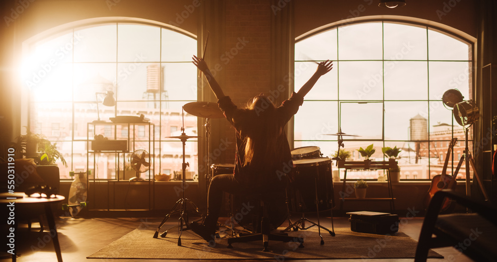 Female or Male with Long Hair Sitting with Their Back to Camera, Playing Drums During a Band Rehearsal in a Loft Studio. Heavy Metal Drummer Practising a Drum Solo Alone At Home.