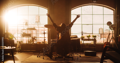 Female or Male with Long Hair Sitting with Their Back to Camera  Playing Drums During a Band Rehearsal in a Loft Studio. Heavy Metal Drummer Practising a Drum Solo Alone At Home.