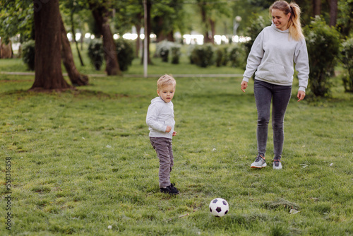 Happy smiling mother and sons playing with football ball outdoors