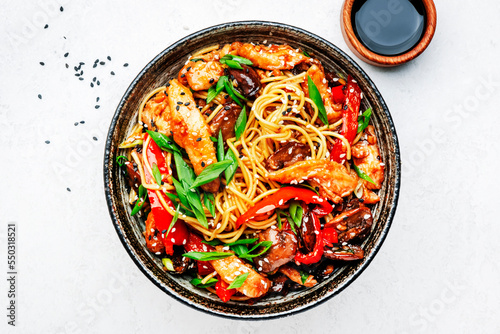 Stir fry egg noodles with chicken, sweet paprika, mushrooms, chives and sesame seeds in bowl. Asian cuisine dish. White table background, top view