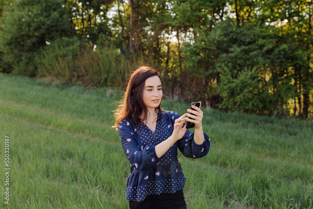 Young woman laughing and typing message in smart phone in the green field Young woman laughing and typing message in smart phone in the green field