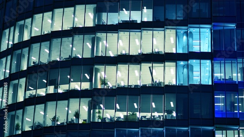 Pattern of office buildings windows illuminated at night. Glass architecture ,corporate building at night - business concept. Blue graphic filter.