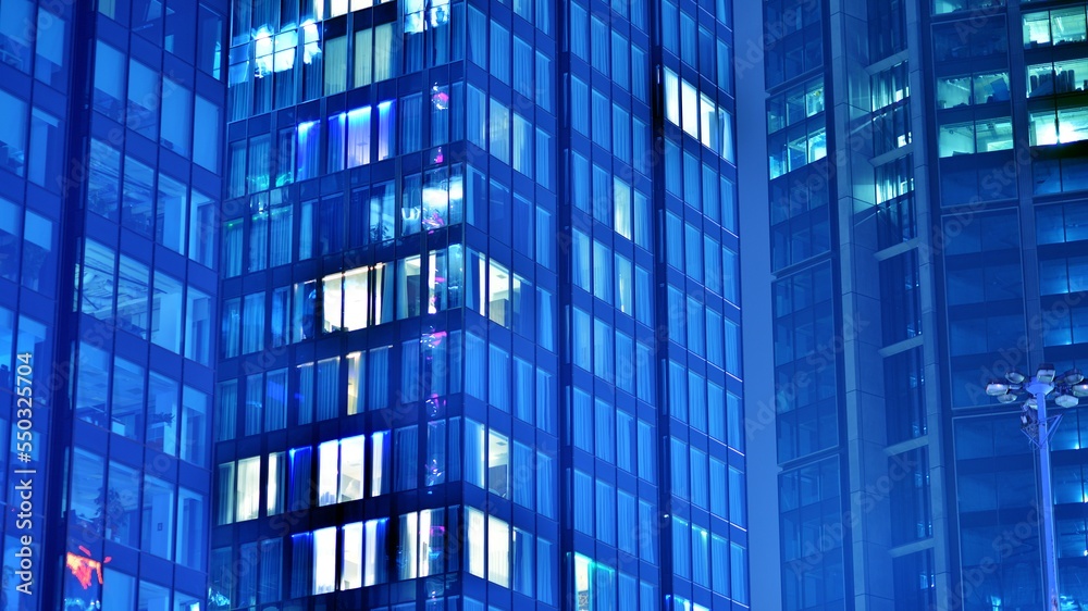 Pattern of office buildings windows illuminated at night. Glass architecture ,corporate building at night - business concept. Blue graphic filter. Pattern of office buildings windows illuminated at night. Glass architecture ,corporate building at night - business concept. Blue graphic filter.