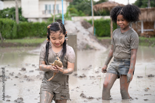 Funny Asia kids girl holding fog with playing in mud puddle