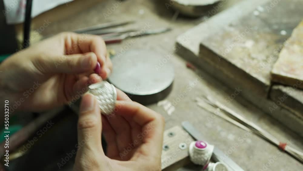 A craftsman is holding a gemstone ring in his hand. At the desk. handmade concept The ring is made of real silver. A craftsman is holding a gemstone ring in his hand. At the desk. handmade concept The ring is made of real silver.