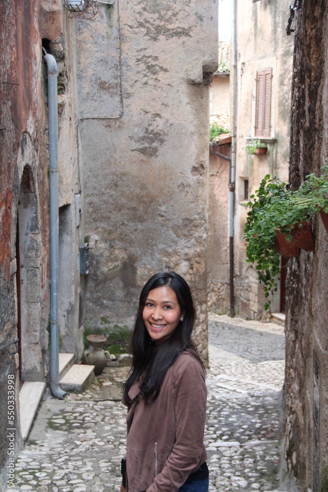 Smiling woman surrounded with brick walls, Sermoneta, Italy