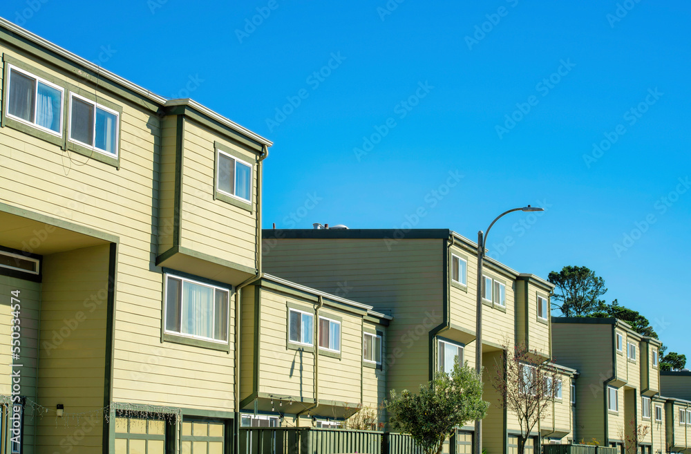 Appartment buildings with block style design and cream or beige exterior made of wood with visible windows and blue sky Appartment buildings with block style design and cream or beige exterior made of wood with visible windows and blue sky