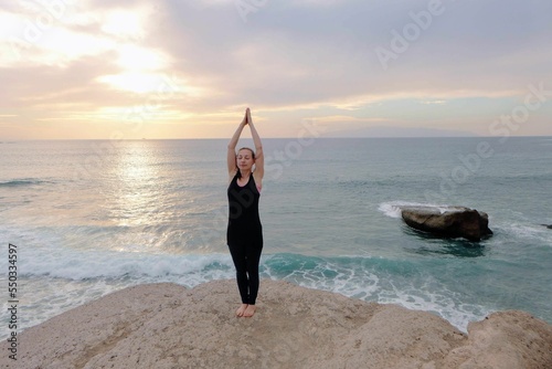 Woman standing in a tadasana pose in front of the beautiful sea photo