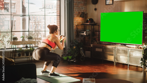 Home Gym: Gorgeous Plus Size Body Positive Girl Training with Using Green Mock-up TV Screen. Authentic Woman Uses Workout Service Fitness App, Streaming Virtual Training with Chroma Key Television
