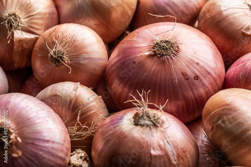 Assorted unpeeled onions in market photo