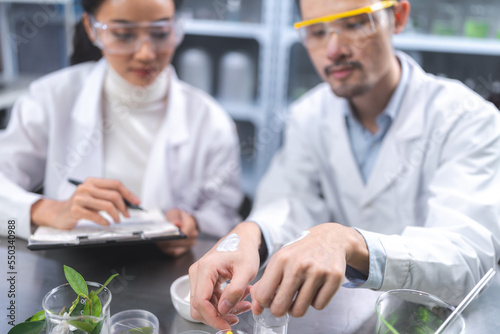 Beauty eco cosmetic research and development concept, Scientist or Pharmacist applying moisturizer lotion on her hand for efficacy testing of natural organic skincare products in laboratory