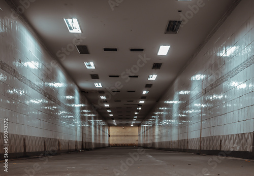 Perspective view of Ambient public underpass with white tiled walls and stripes of ceiling neon lights. Long pedestrian luminous tunnel, Space for text, Selective focus. photo