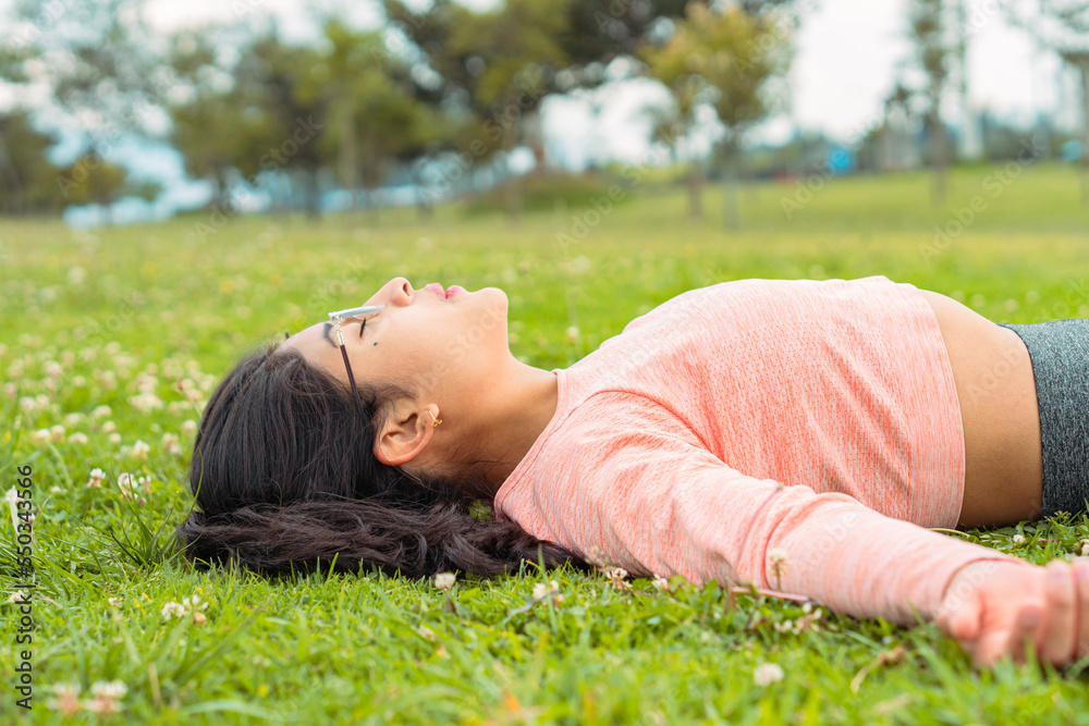 Tired sportswoman lying on lawn in park Tired sportswoman lying on lawn in park