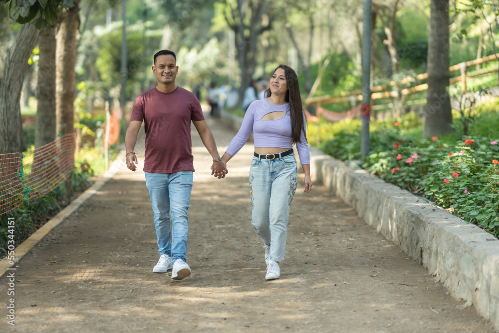 Happy couple holding hands and walking in park Happy couple holding hands and walking in park