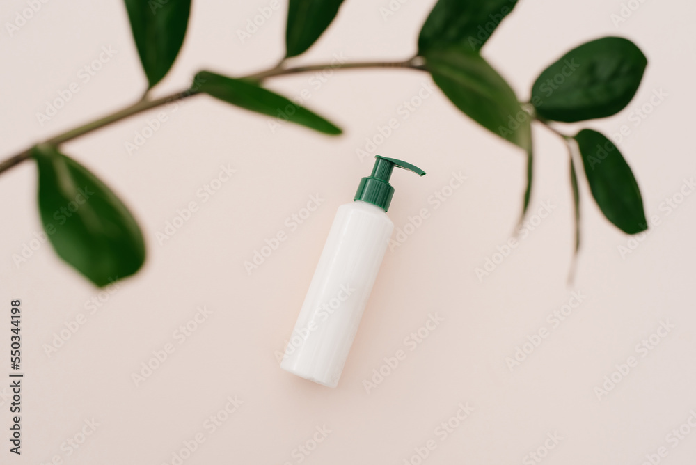 White cosmetic bottle of cream with a top view of the leaves of plants, a mock-up of the product design. Natural organic cosmetics White cosmetic bottle of cream with a top view of the leaves of plants, a mock-up of the product design. Natural organic cosmetics