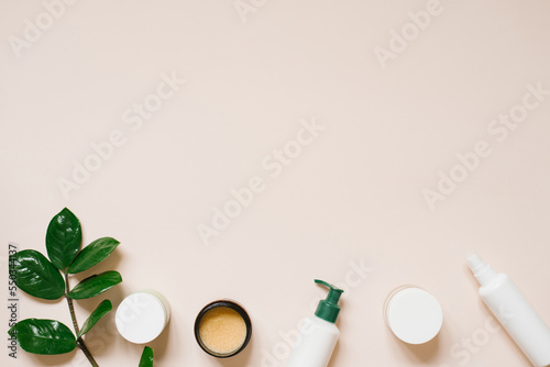 Minimal composition with skin care cosmetics and green on a pastel beige background. Flat lay, copy space.