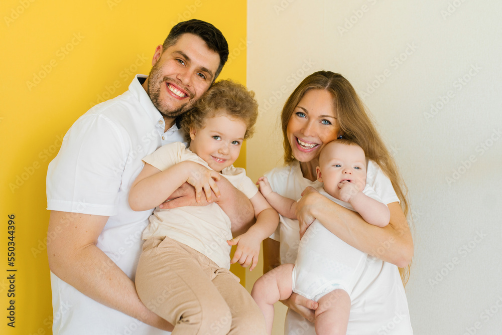 Young sincere family, where a happy father and mother hold their lovely children in their arms. Family photo shoot in the studio