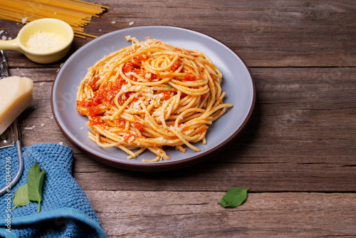 Delicious spaghetti cheese pasta served on a plate Vegetables, Italian tomato sauce and spices arranged on a wooden table, top view