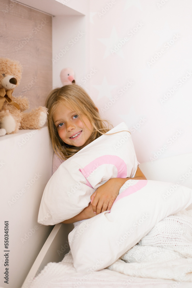 Beautiful girl hugs a pillow on the bed in the nursery Beautiful girl hugs a pillow on the bed in the nursery