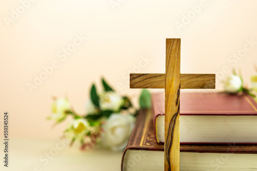 Canvas Print Religion composition with wooden cross with closed red Christian bibles with white flowers on a light gradient background with copy space