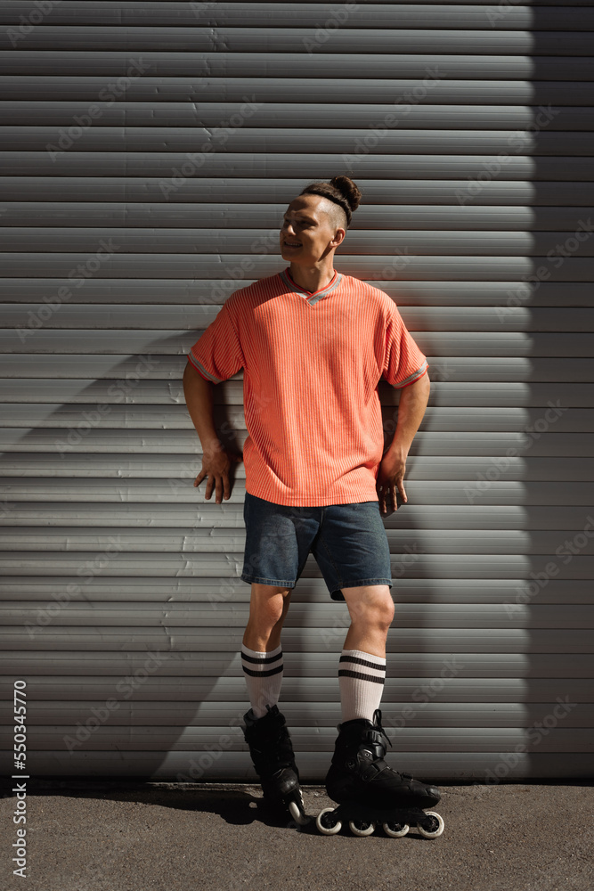 Smiling young man in roller blades standing near building outside.