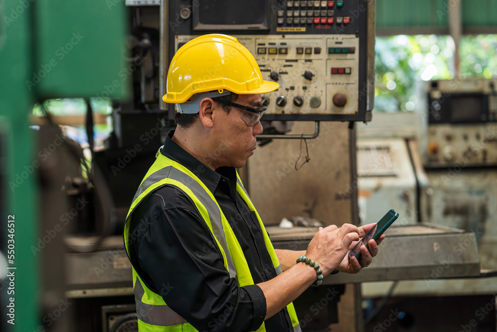 Engineer with mobile phone. Man technician is working in a steel factory. Man worker in safety helmet working on steel machine. Engineer with mobile phone. Man technician is working in a steel factory. Man worker in safety helmet working on steel machine.
