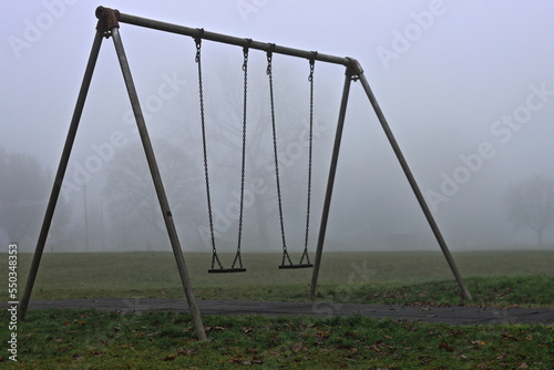Fototapeta Naklejka Na Ścianę i Meble -  A empty swingset on a foggy autumn morning.