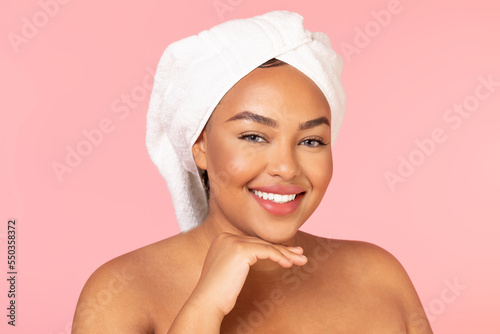 After spa concept. Portrait of chubby black woman with bath towel on head and perfect glowing skin smiling at camera