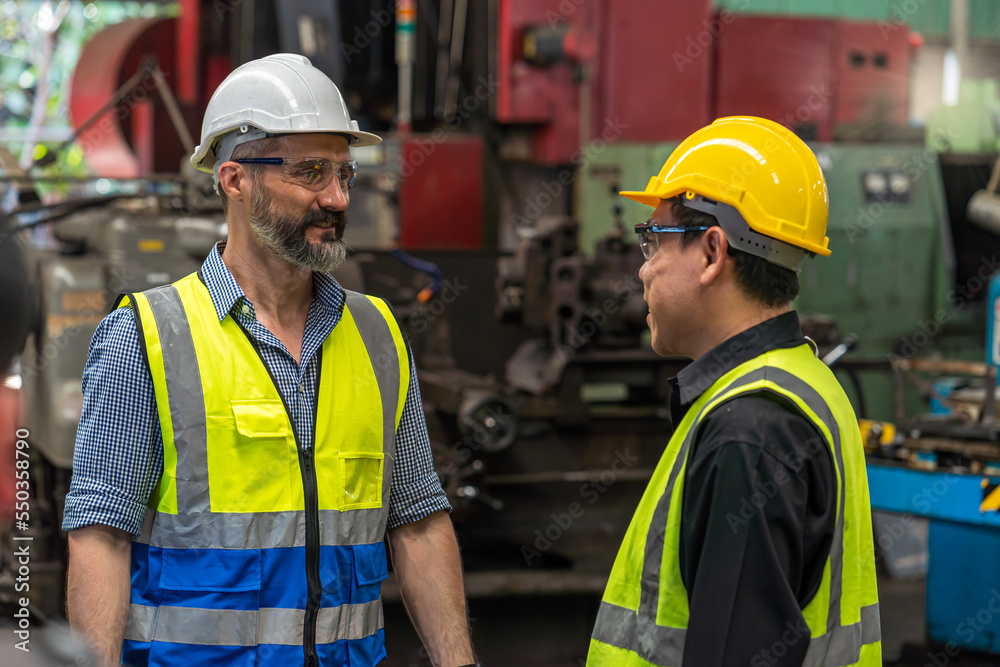 Engineer discuss with Technician in factory. Man technician is working in a steel factory. Man worker in safety helmet working on steel machine. Engineer discuss with Technician in factory. Man technician is working in a steel factory. Man worker in safety helmet working on steel machine.