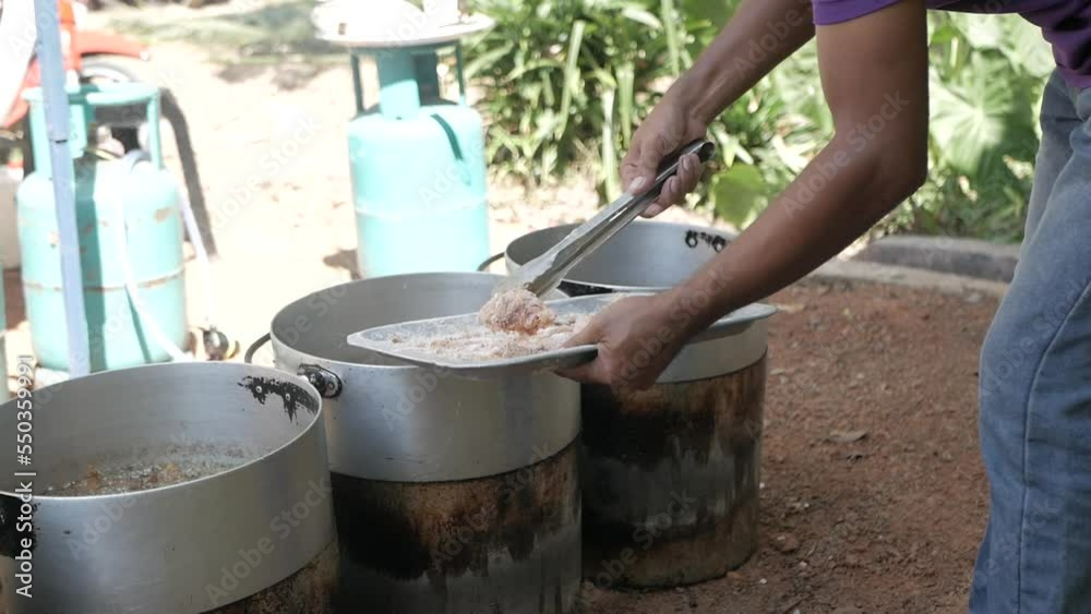 A man putting flour coated chicken into deep fry pan A man putting flour coated chicken into deep fry pan