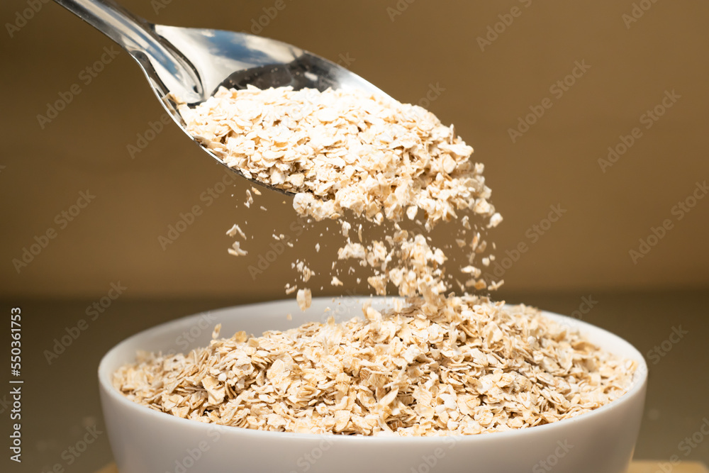Avena molida siendo vertida en un bol blanco con una cuchara de metal