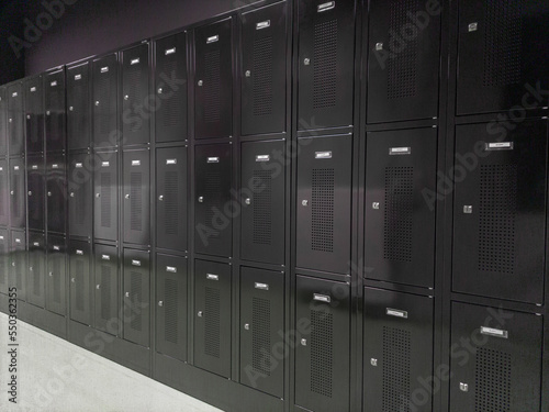 Wall of black shiny locker cabinets in an industrial environment. Image taken in Belgium, Leuven, Herestraat.