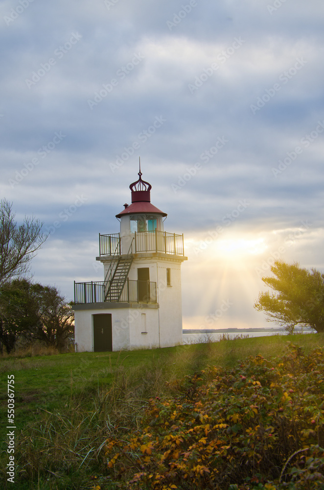 Lighthouse, Spodsbjerg Fyr in Huntsted on the coast of Denmark. Sun rays shining Lighthouse, Spodsbjerg Fyr in Huntsted on the coast of Denmark. Sun rays shining