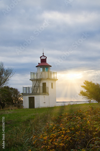 Lighthouse, Spodsbjerg Fyr in Huntsted on the coast of Denmark. Sun rays shining