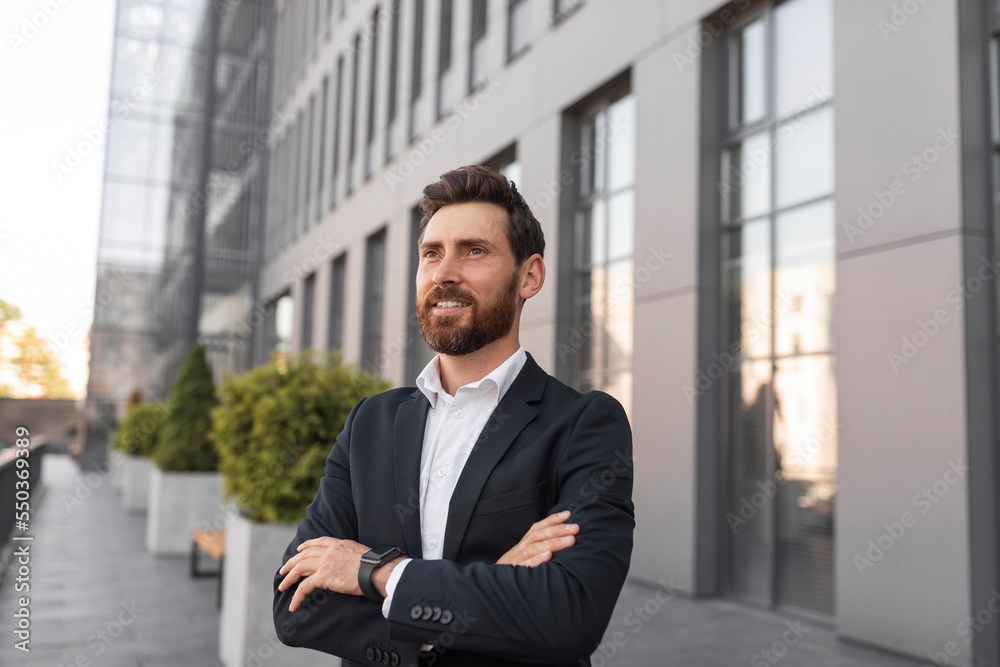 Confident cheerful young european man ceo manager with beard crossed arms over chest and looks at empty space Confident cheerful young european man ceo manager with beard crossed arms over chest and looks at empty space