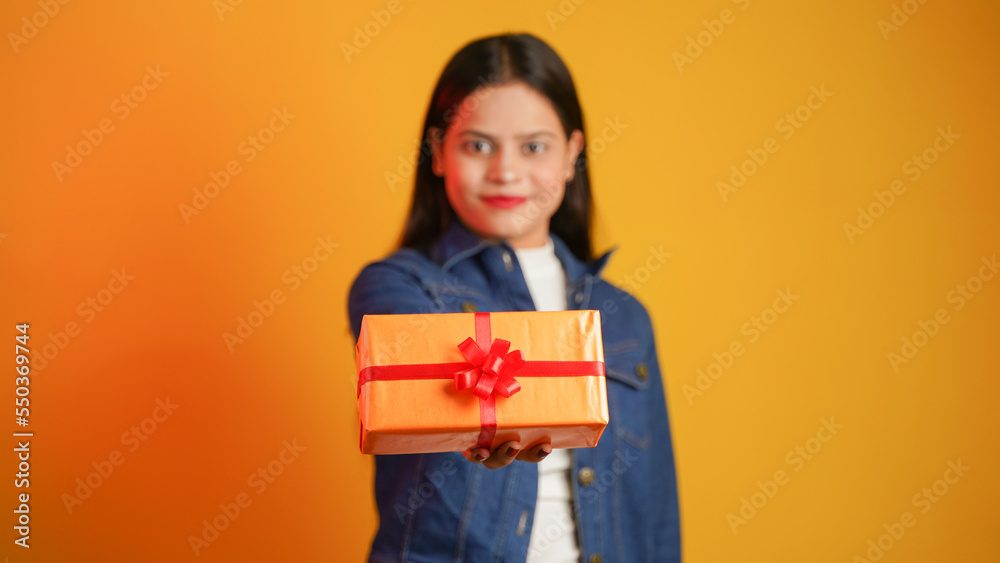 Portrait of an attractive cheerful happy girl holding gift box in hand, Young Asian Indian woman with gifts isolated over color background Portrait of an attractive cheerful happy girl holding gift box in hand, Young Asian Indian woman with gifts isolated over color background