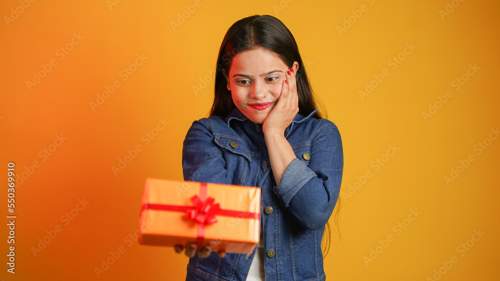 Portrait of an attractive cheerful happy girl holding gift box in hand, Young Asian Indian woman with gifts isolated over color background Portrait of an attractive cheerful happy girl holding gift box in hand, Young Asian Indian woman with gifts isolated over color background