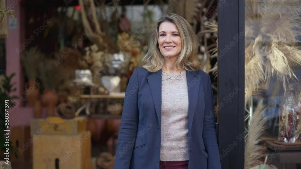 Portrait of a female business owner of Flower Store wearing blue jacket standing in front local small business shop Portrait of a female business owner of Flower Store wearing blue jacket standing in front local small business shop