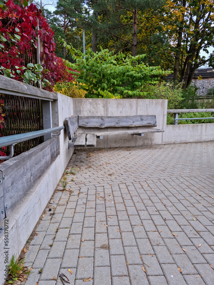 Obraz premium Bench at the public park. Modern recreation place. Pathway in perspective. Concrete and timber in modern architecture.
