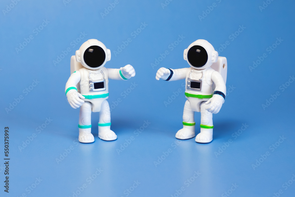 Fototapeta premium Plastic figurines of an astronauts in a spacesuit on a blue background. Children's toys astronauts. Fascination with space, the study of planets.