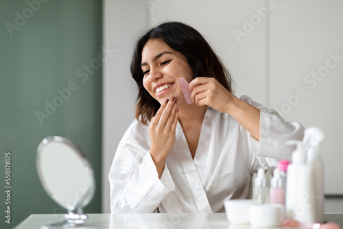 Happy arab woman using natural massager  enjoying healthy glowing skin