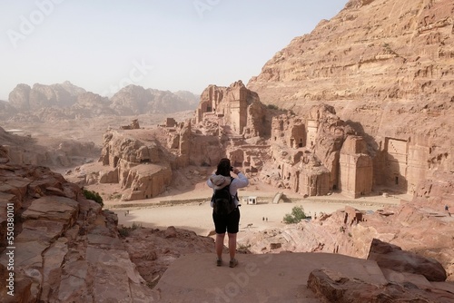 Silhouette of woman standing on rock and taking photo of Petra, Jordan. Petra is ancient Nabataean city, considered one of seven new wonders of world and is world heritage site.