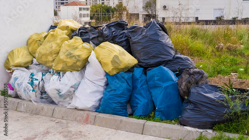 Close-up of a large mountain of garbage bags collected by volunteers to protect the environment. Pollution of the environment by plastic and other human waste.
