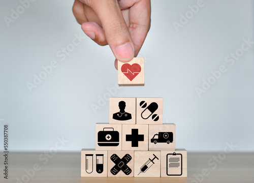Health Insurance Concept, Hand of man holding wood cube stacking with icon healthcare medical on blue background, copy space.