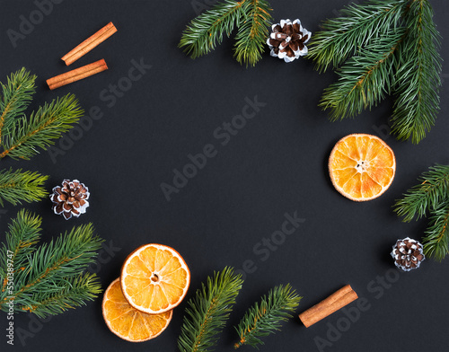 Frame for your text made of spruce branches of cones, oranges and cinnamon with a dark background photo