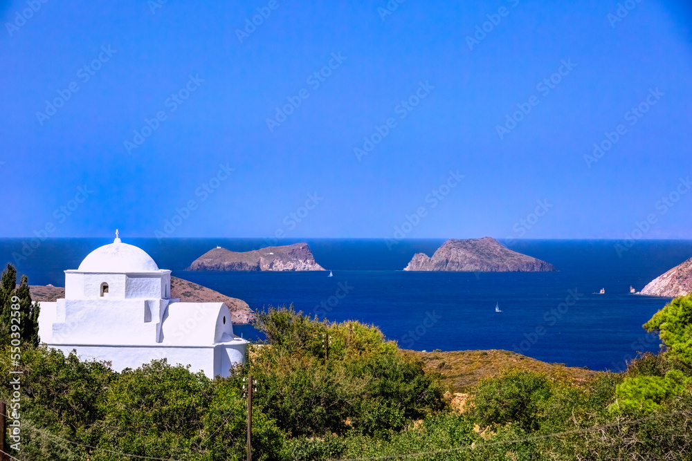Traditional chapel with sailing boats at the background, in Milos island, Cyclades, Greece