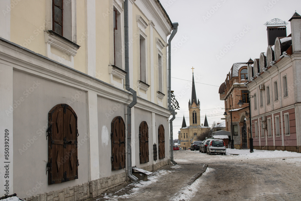Architecture old medieval town Lutsk Ukraine. Winter view on old city paving stone street and history buildings. National landmark in snow. Tourist famous attraction.